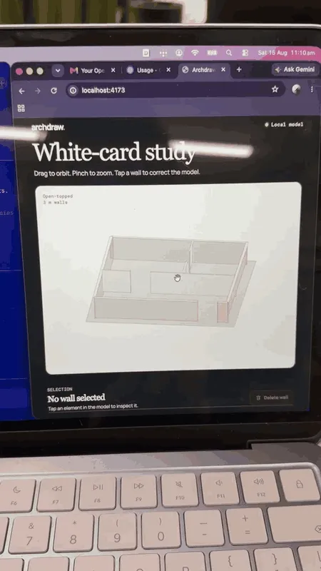 Archdraw on the laptop at the end of the morning, the white card model it built turning as the cursor orbits it, open topped walls on a pale grey ground.